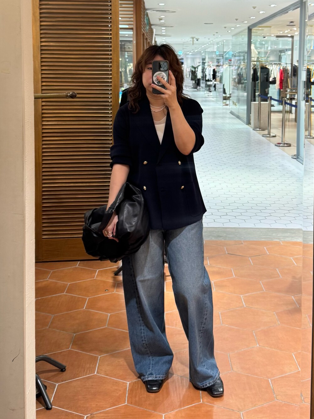 ブラック系のショルダーバッグ、ブルー系のデニムパンツ、ブルー系のテーラードジャケットを着用したレディースの夏コーディネートの2枚目の写真