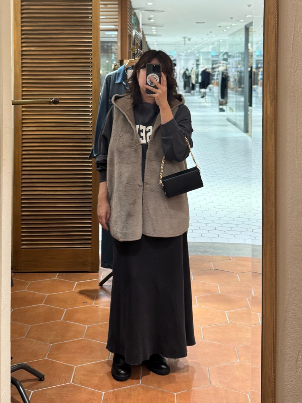 グレー系のスウェット、グレー系のスカート、ブラック系のブーツを着用したレディースの秋コーディネートの2枚目の写真