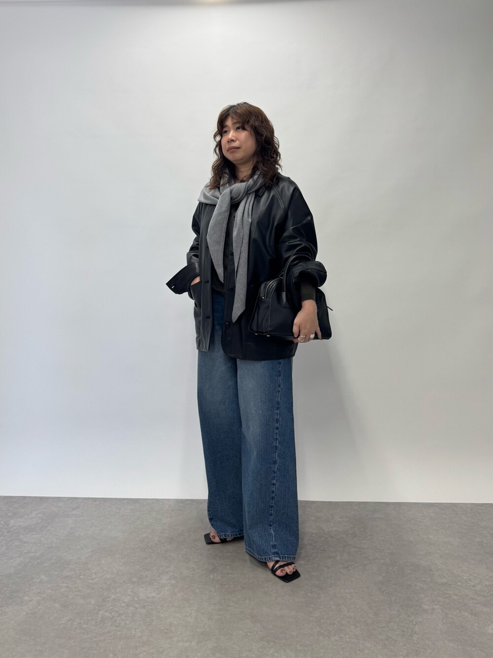 ブルー系のデニムパンツ、グリーン系のニット/セーター、ブラック系のボストンバッグを着用したレディースの夏コーディネートの3枚目の写真