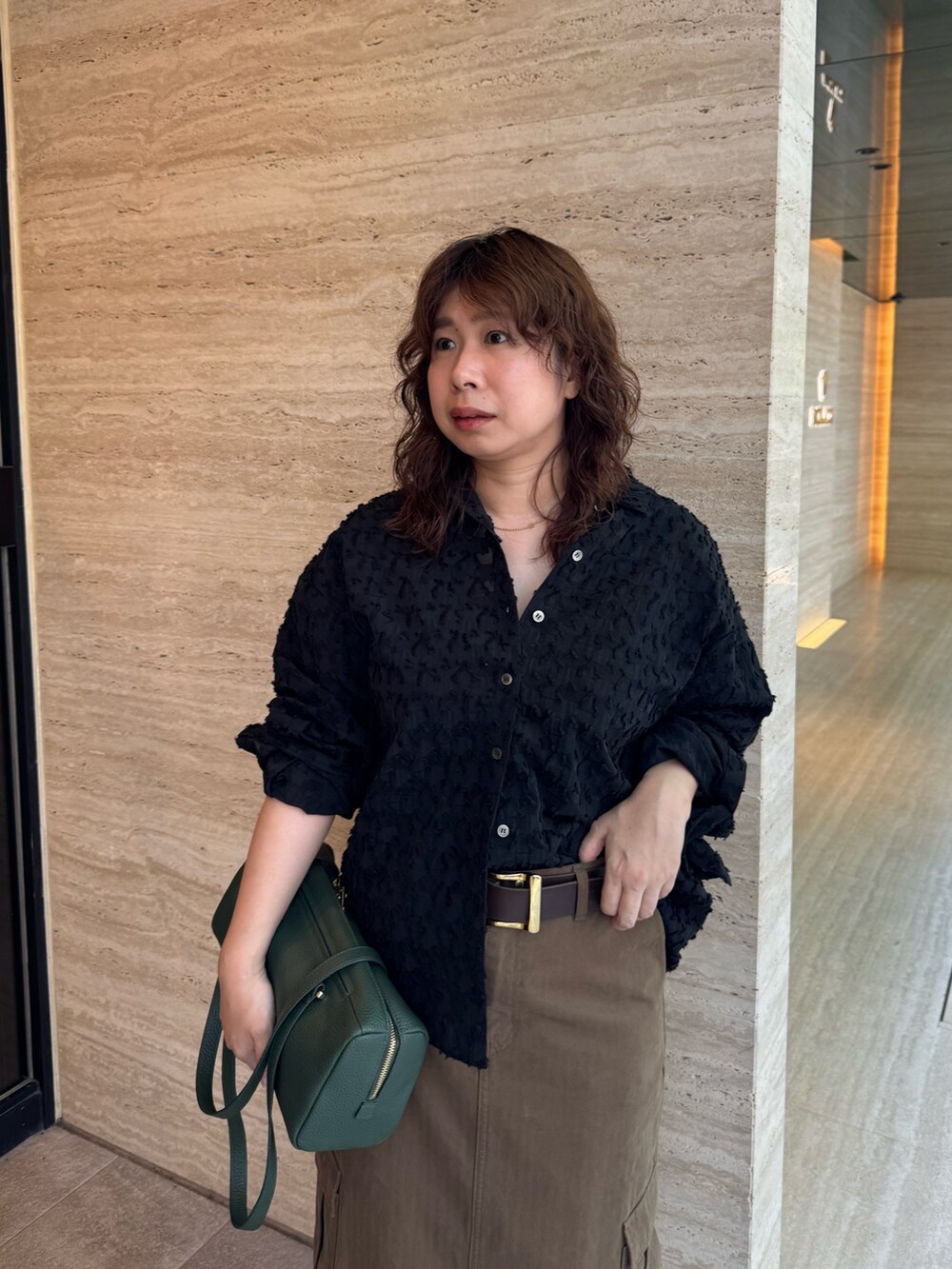 ブラウン系のスカート、ブラック系のローファー、グリーン系のショルダーバッグを着用したレディースの夏コーディネートの4枚目の写真