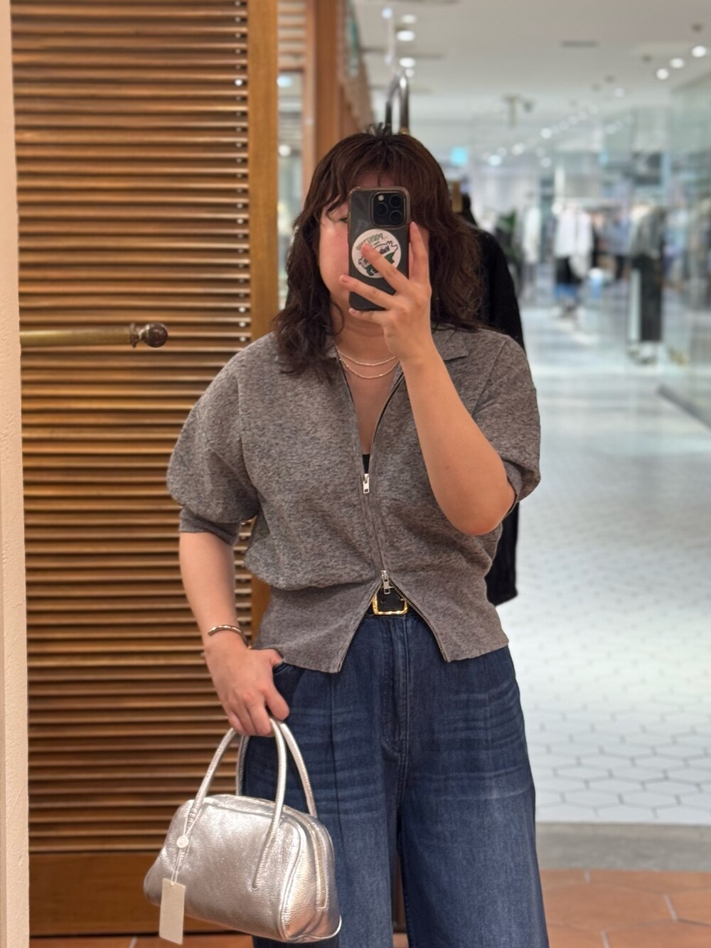 ブルー系のデニムパンツ、ブラック系のサンダル、グレー系のパーカーを着用したレディースの夏コーディネートの2枚目の写真