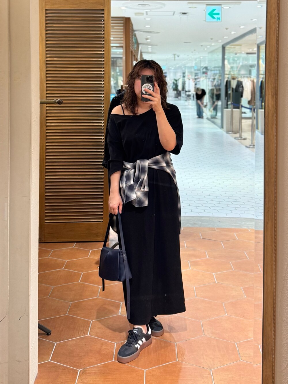 ブルー系のショルダーバッグ、ブラック系のワンピース、ブルー系のシャツ/ブラウスを着用したレディースの夏コーディネートの2枚目の写真