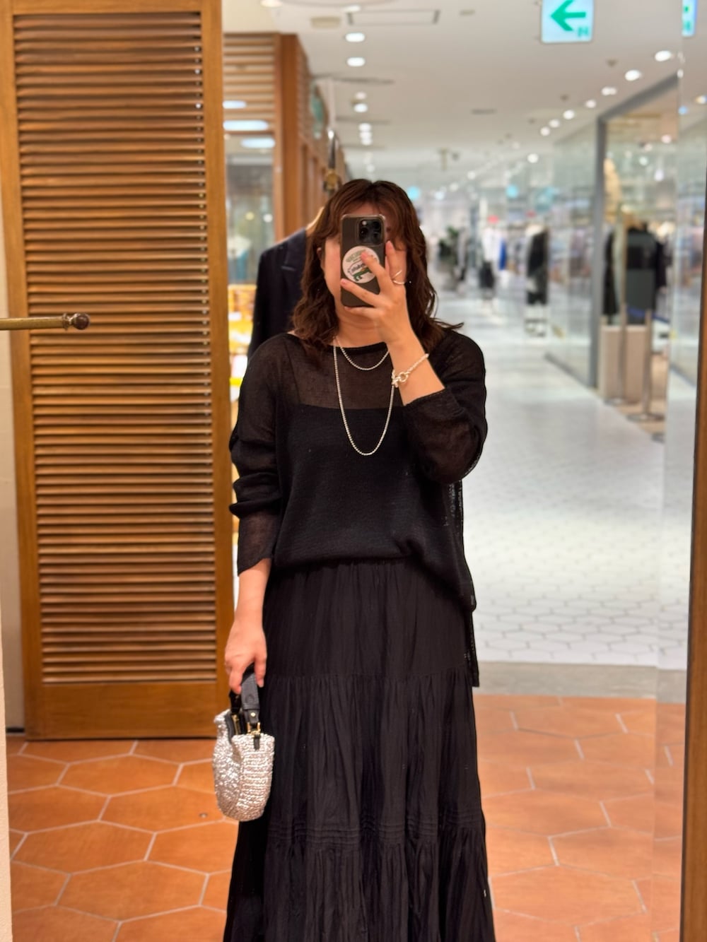 ブラウン系のテーラードジャケット、ブラック系のスカート、ブラック系のニット/セーターを着用したレディースの夏コーディネートの2枚目の写真