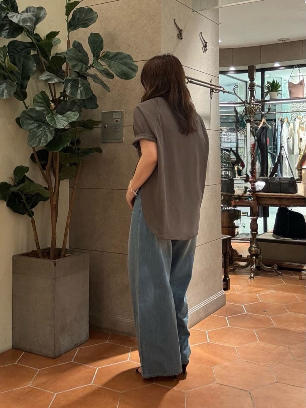 ブルー系のデニムパンツ、ブラック系のブルゾン、ブラウン系のTシャツ/カットソーを着用したレディースの夏コーディネートの4枚目の写真