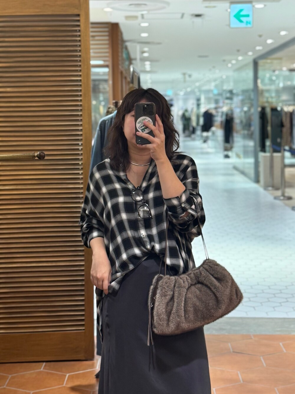 ブラウン系のハンドバッグ、グレー系のスカート、ブラック系のブーツを着用したレディースの秋コーディネートの3枚目の写真