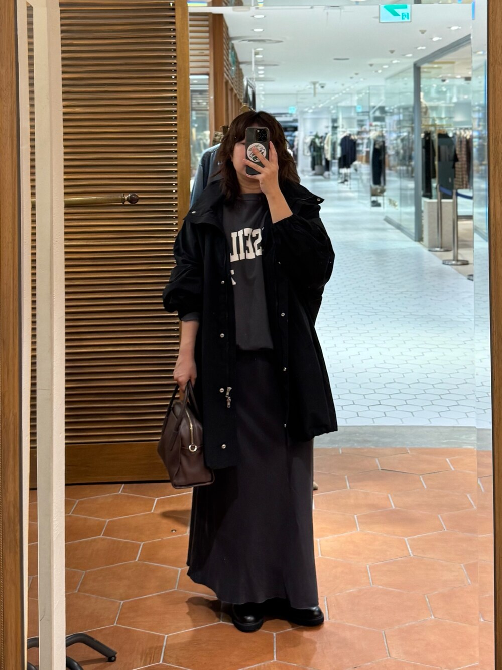 ブラウン系のボストンバッグ、グレー系のスカート、ブラック系のブーツを着用したレディースの秋コーディネートの2枚目の写真