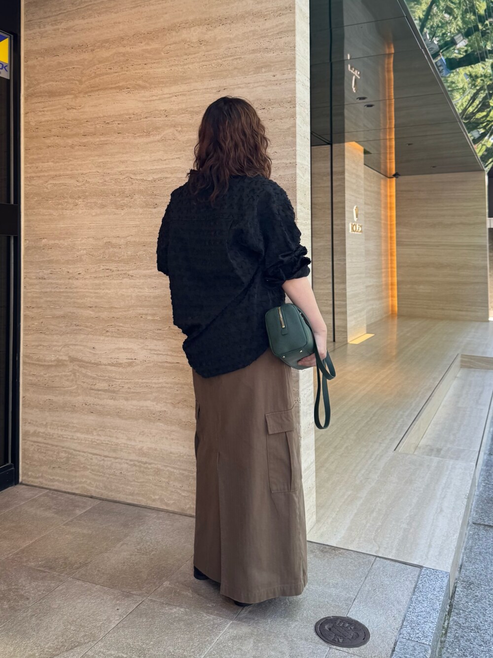 ブラウン系のスカート、ブラック系のローファー、グリーン系のショルダーバッグを着用したレディースの夏コーディネートの2枚目の写真