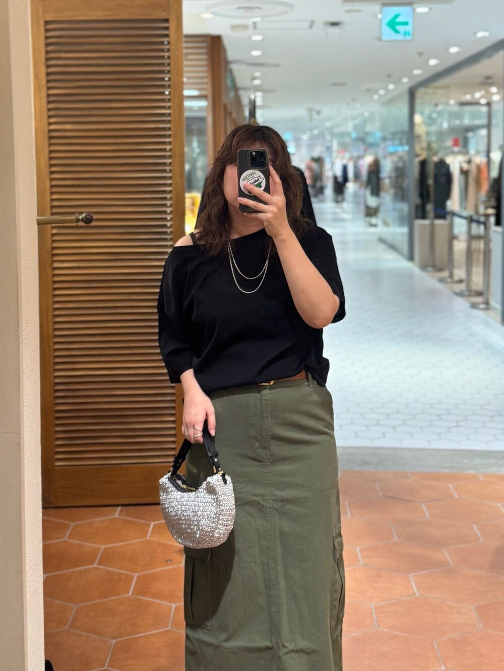 グリーン系のスカート、ブラック系のTシャツ/カットソー、イエロー系のベルトを着用したレディースの夏コーディネートの2枚目の写真