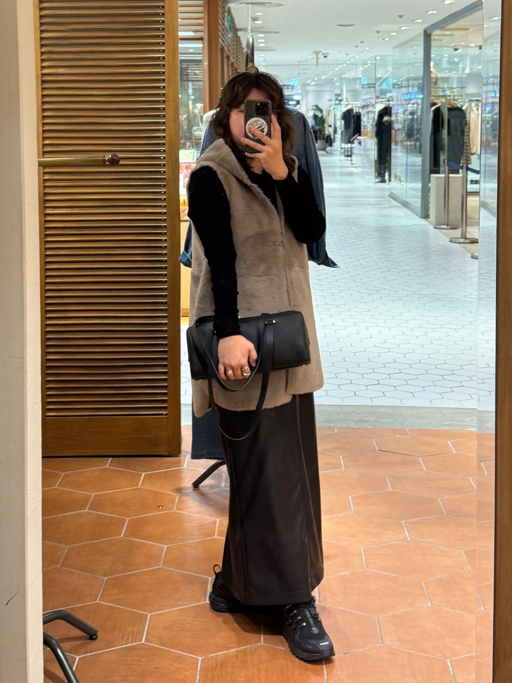 ブラック系のスカート、ブラック系のショルダーバッグ、ブラック系のTシャツ/カットソーを着用したレディースの秋コーディネートの2枚目の写真