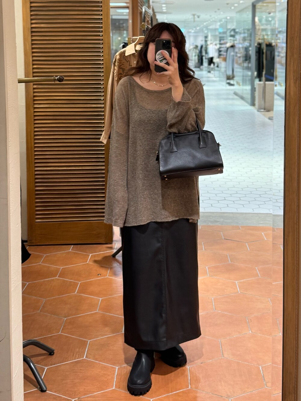 ブラック系のスカート、ブラック系のボストンバッグ、ブラック系のブーツを着用したレディースの秋コーディネートの2枚目の写真