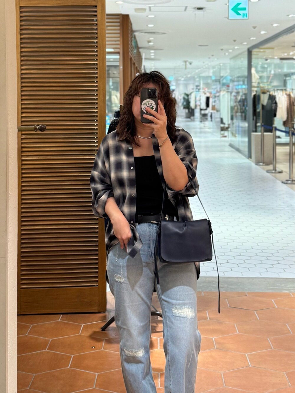 ブラック系のキャミソール、ブルー系のデニムパンツ、ブルー系のショルダーバッグを着用したレディースの夏コーディネートの2枚目の写真