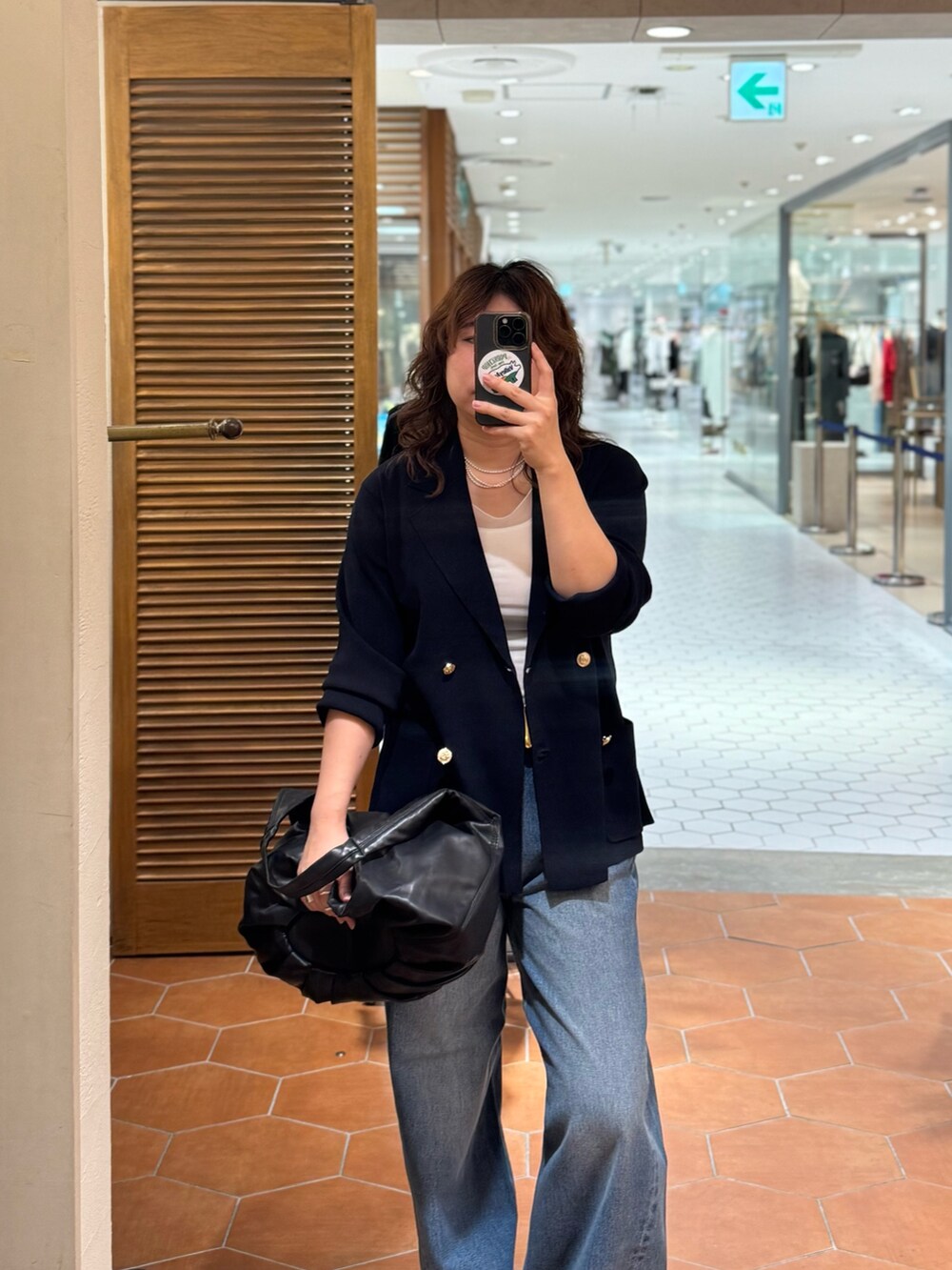 ブラック系のショルダーバッグ、ブルー系のデニムパンツ、ブルー系のテーラードジャケットを着用したレディースの夏コーディネートの3枚目の写真