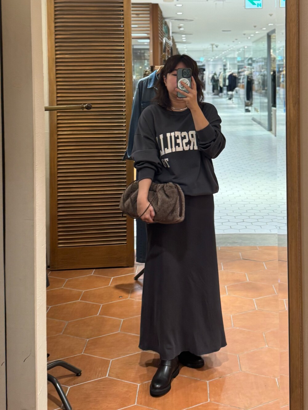 ブラウン系のボストンバッグ、グレー系のスカート、ブラック系のブーツを着用したレディースの秋コーディネートの3枚目の写真