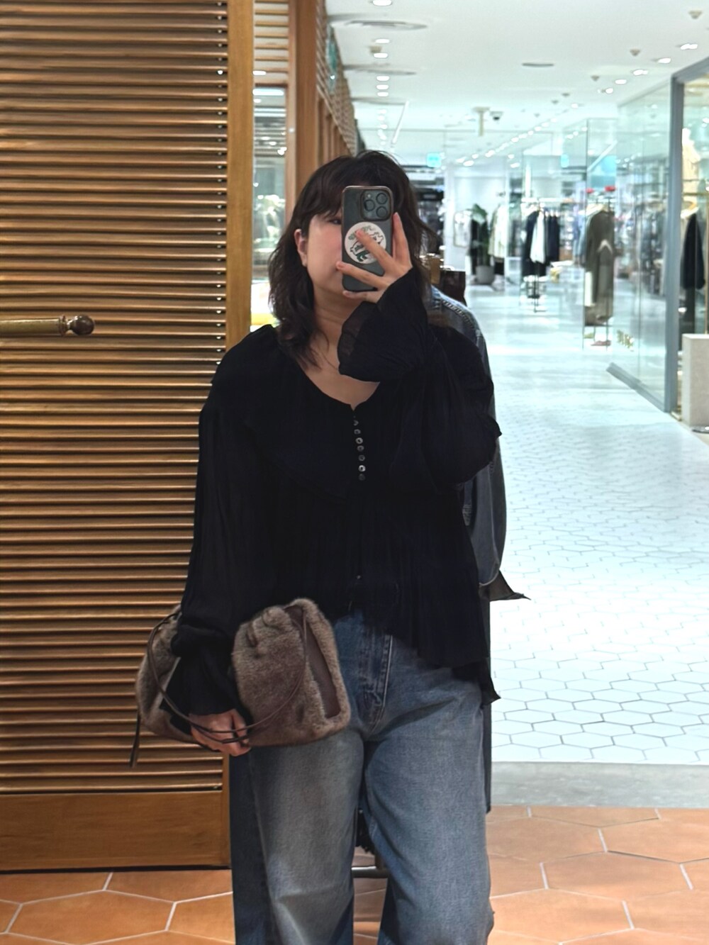 ブルー系のデニムパンツ、ベージュ系のその他シューズ、ブラウン系のハンドバッグを着用したレディースの夏コーディネートの3枚目の写真