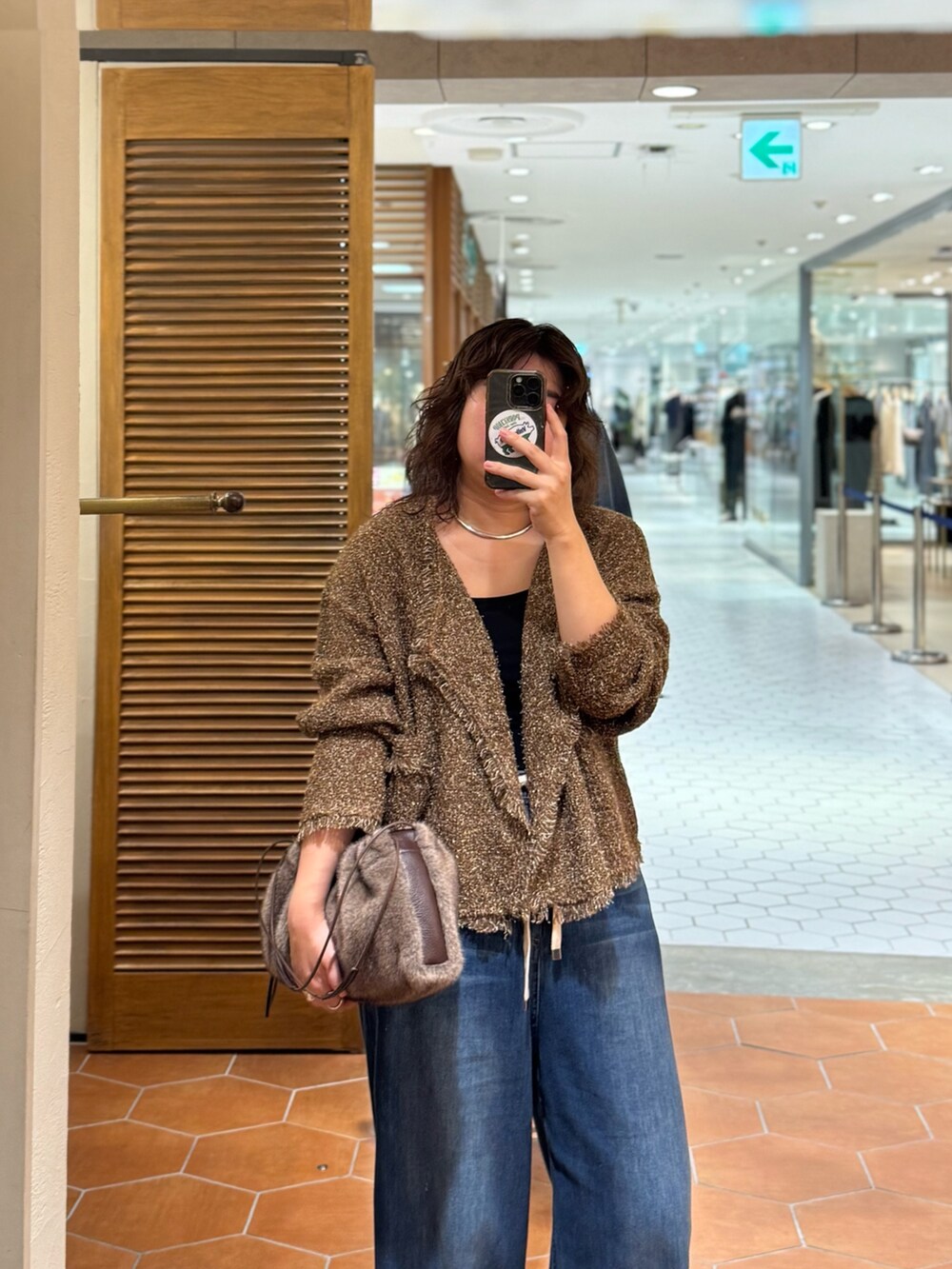 ブラック系のパンプス、ブルー系のデニムパンツ、ブラウン系のハンドバッグを着用したレディースの秋コーディネートの2枚目の写真