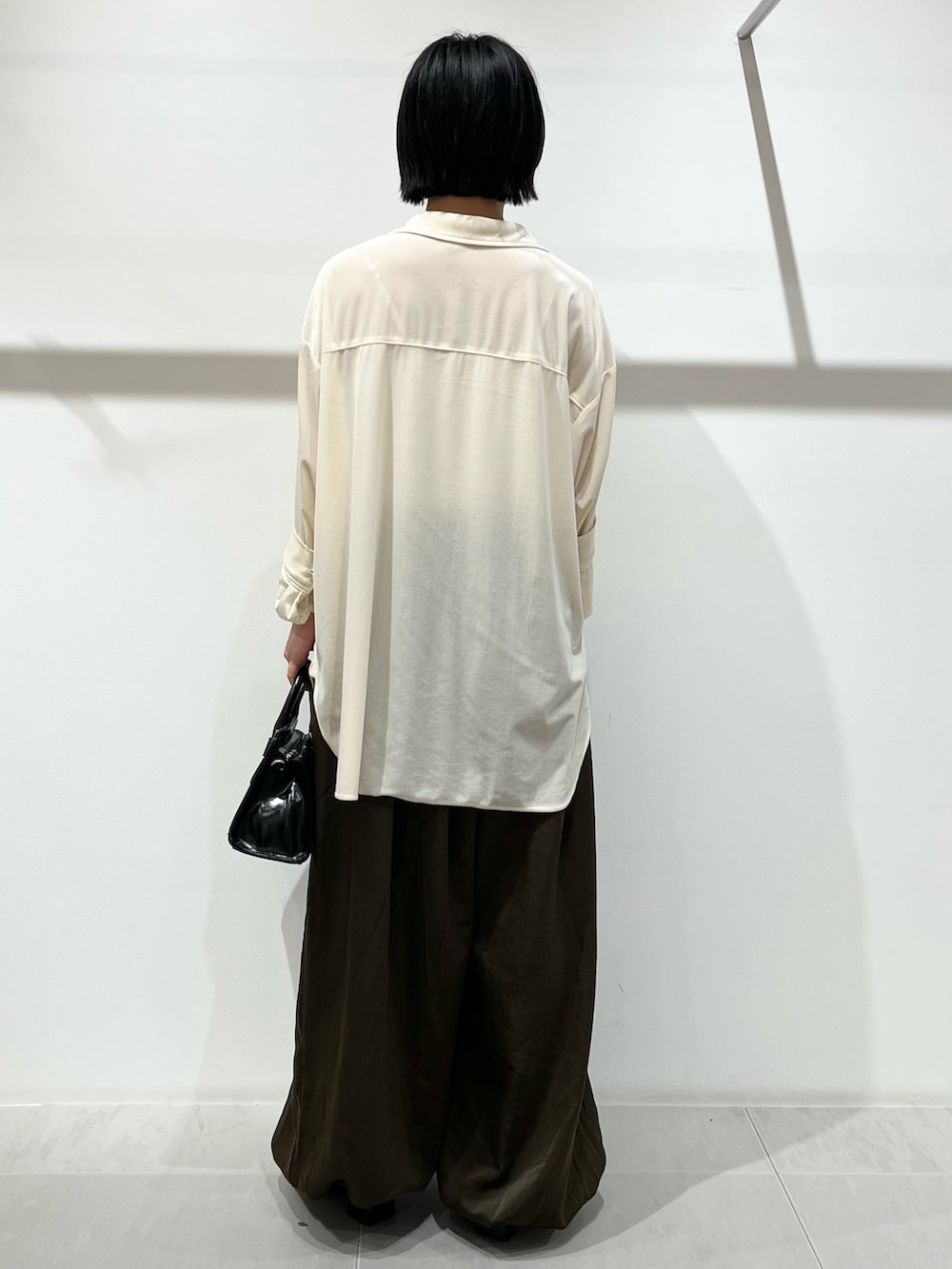 ブラック系のボストンバッグ、ホワイト系のシャツ/ブラウス、ブラック系のパンプスを着用したレディースの冬コーディネートの3枚目の写真