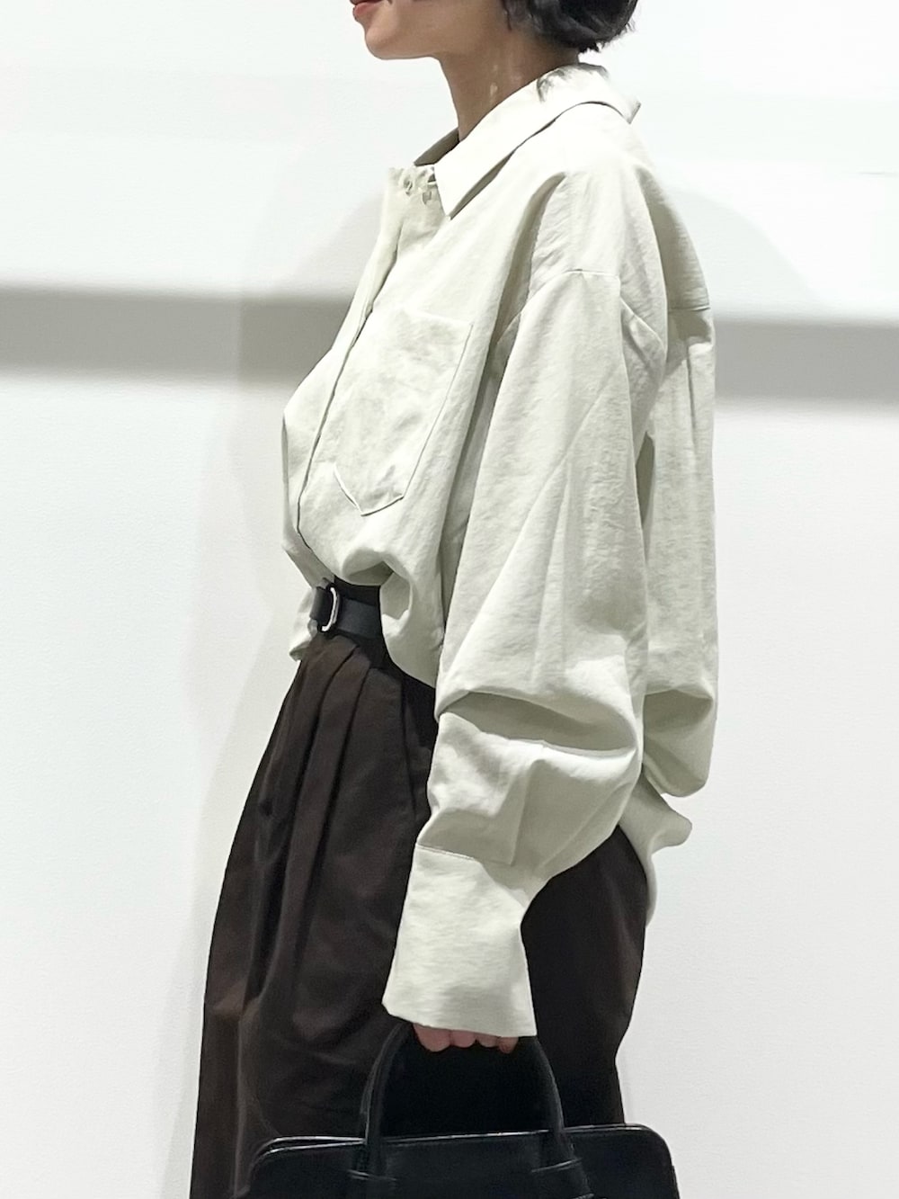 ブラック系のボストンバッグ、ブラック系のパンプス、グリーン系のシャツ/ブラウスを着用したレディースの春コーディネートの4枚目の写真