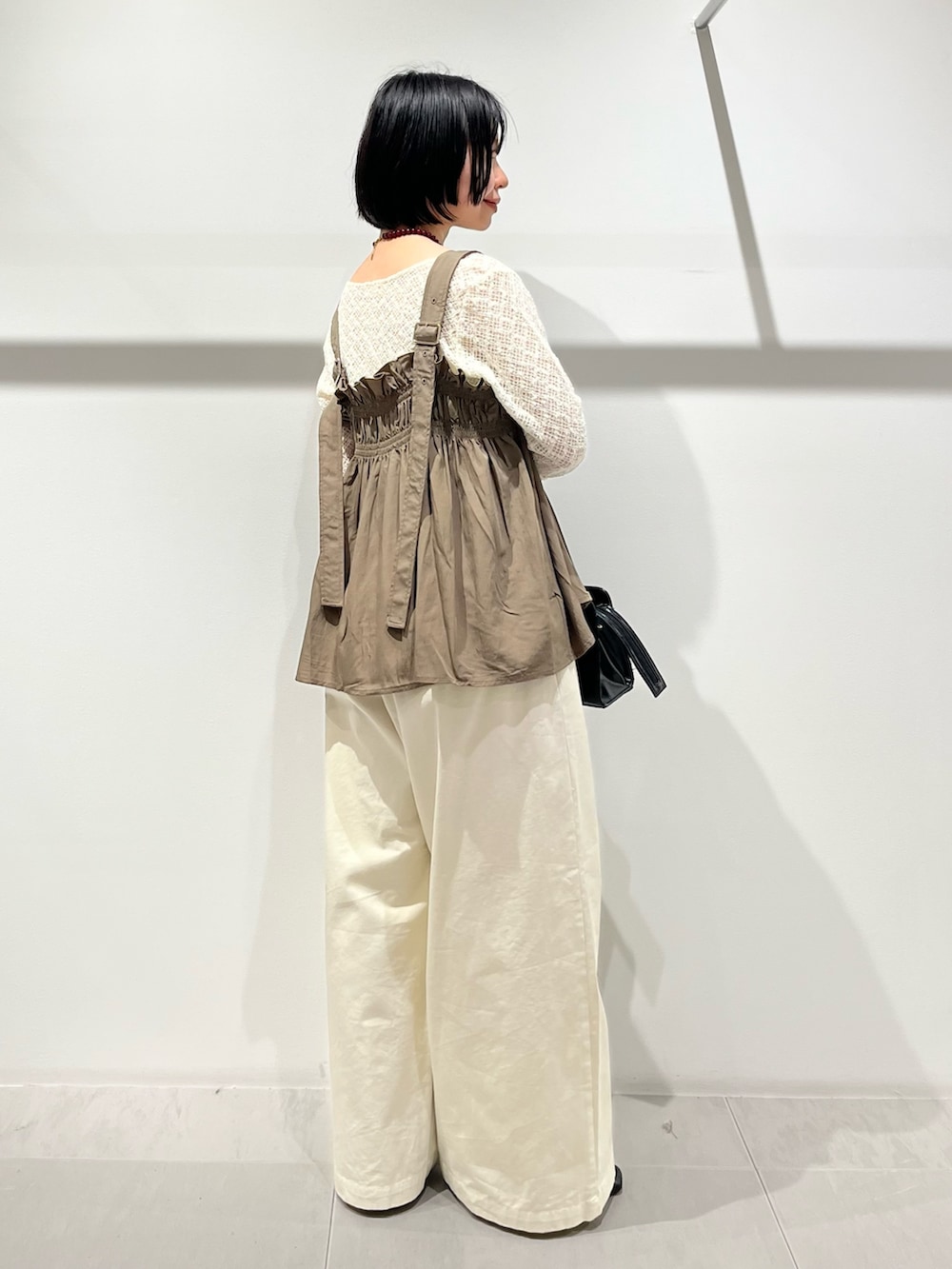 グリーン系のその他トップス、ブラック系のその他シューズ、ホワイト系のその他パンツを着用したレディースの春コーディネートの2枚目の写真