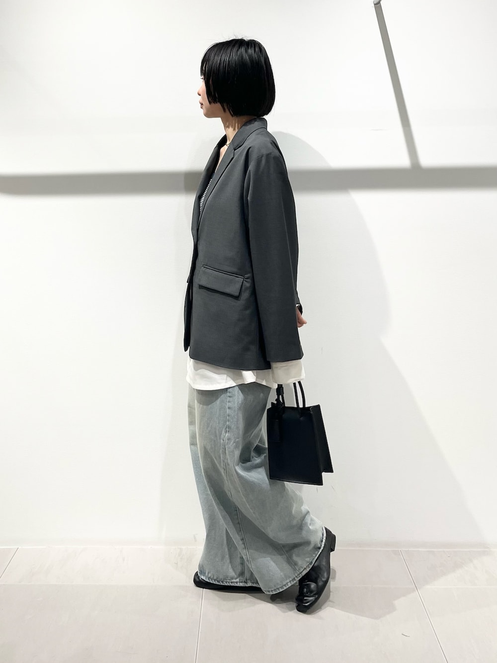 ブラック系のハンドバッグ、ブラック系のその他シューズ、ブルー系のデニムパンツを着用したレディースの春コーディネートの2枚目の写真