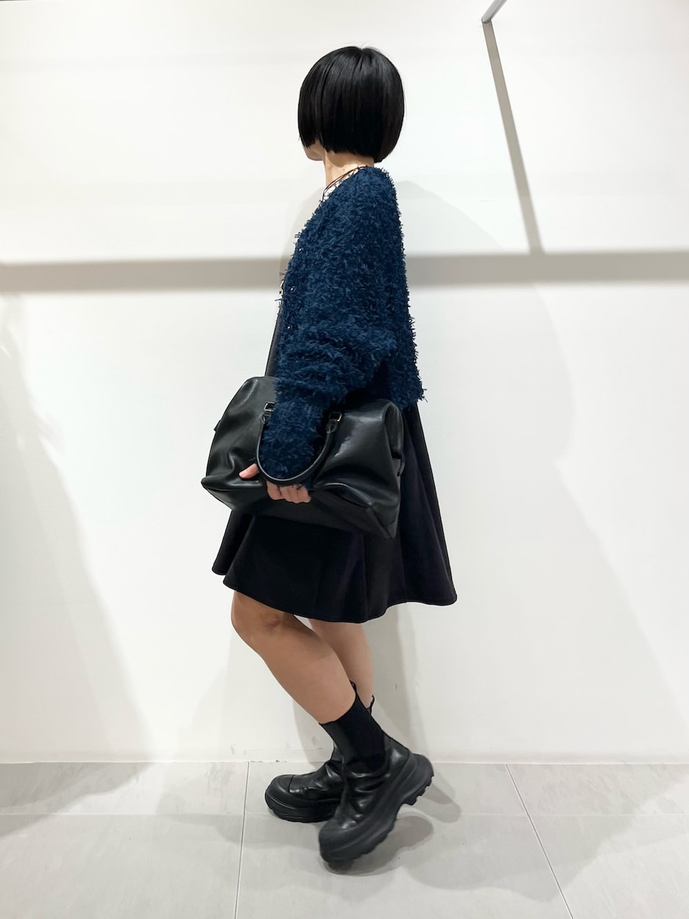 ブルー系のニット/セーター、ブラック系のブーツ、ブラック系のボストンバッグを着用したレディースの秋コーディネートの2枚目の写真