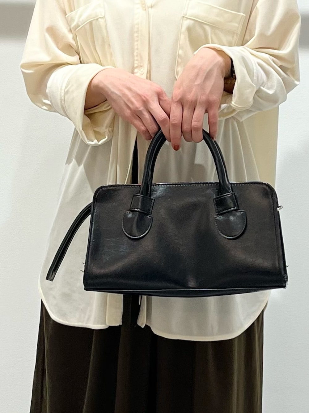 ブラック系のボストンバッグ、ホワイト系のシャツ/ブラウス、ブラック系のパンプスを着用したレディースの冬コーディネートの5枚目の写真