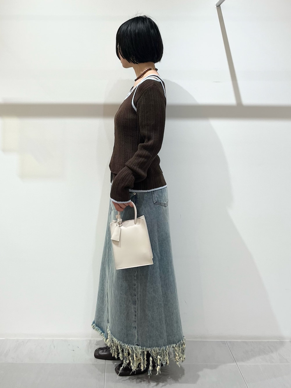 ブラウン系のその他シューズ、ブルー系のスカート、ホワイト系のハンドバッグを着用したレディースの春コーディネートの2枚目の写真