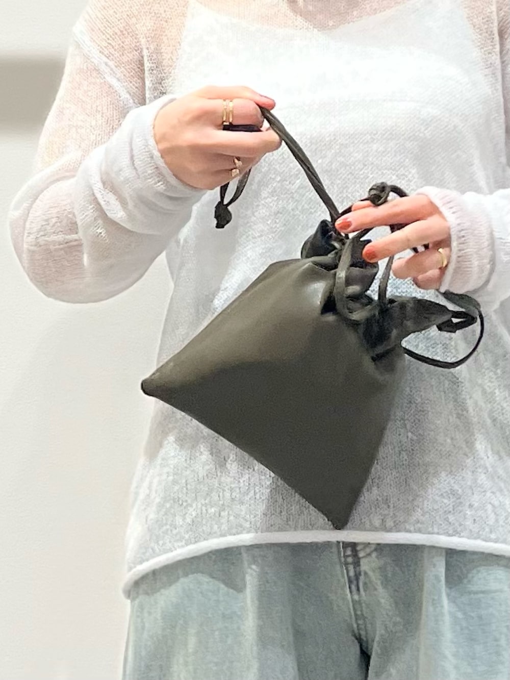 ブラック系のその他シューズ、グリーン系のショルダーバッグ、ブルー系のデニムパンツを着用したレディースの冬コーディネートの5枚目の写真