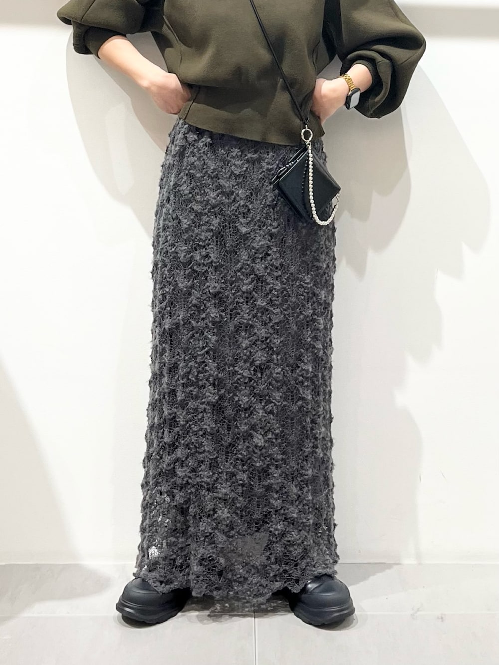 グリーン系のニット/セーター、ブラック系のブーツ、グレー系のスカートを着用したレディースの秋コーディネートの5枚目の写真