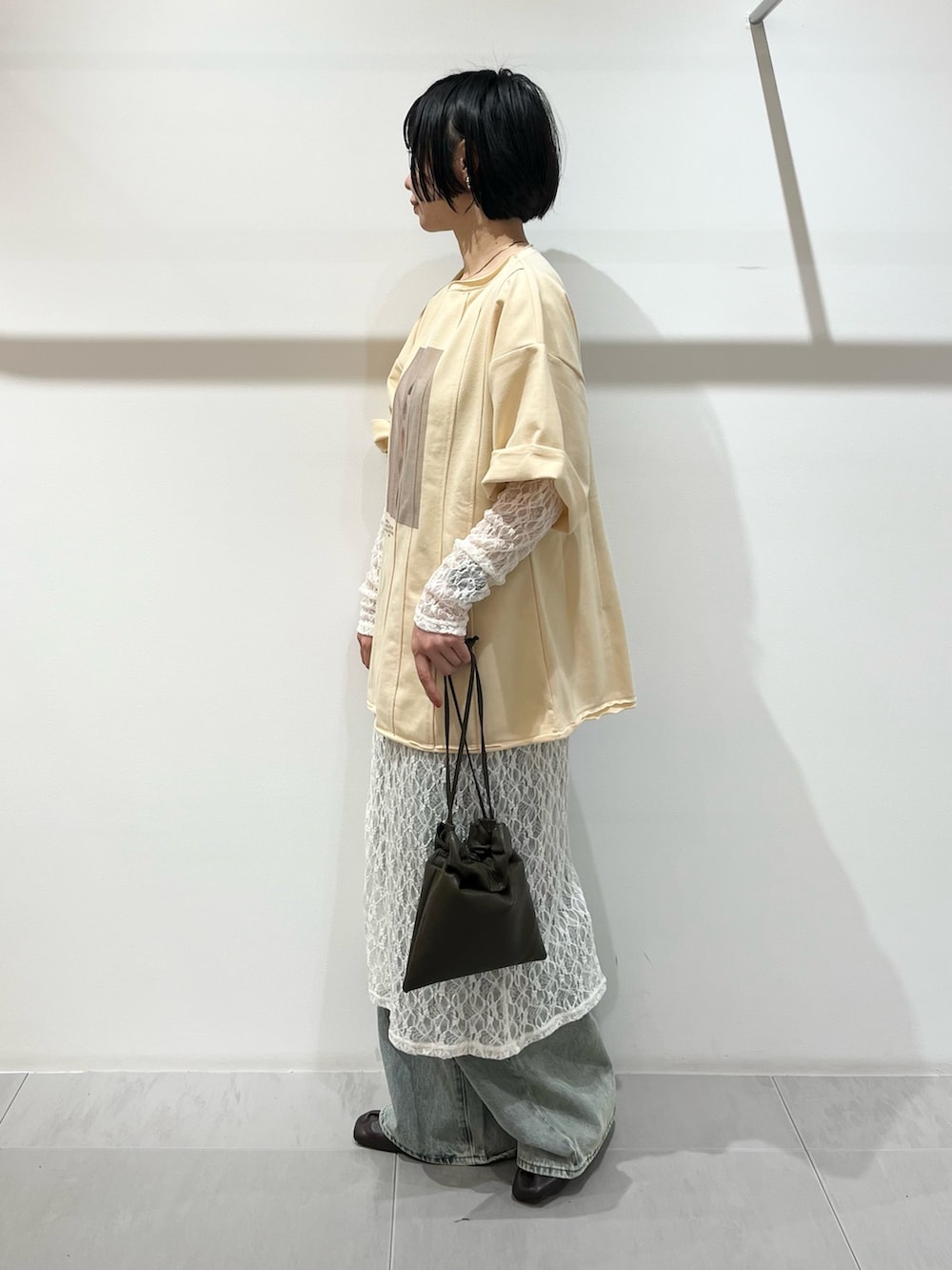 イエロー系のTシャツ/カットソー、ホワイト系のワンピース、グリーン系のショルダーバッグを着用したレディースの春コーディネートの2枚目の写真