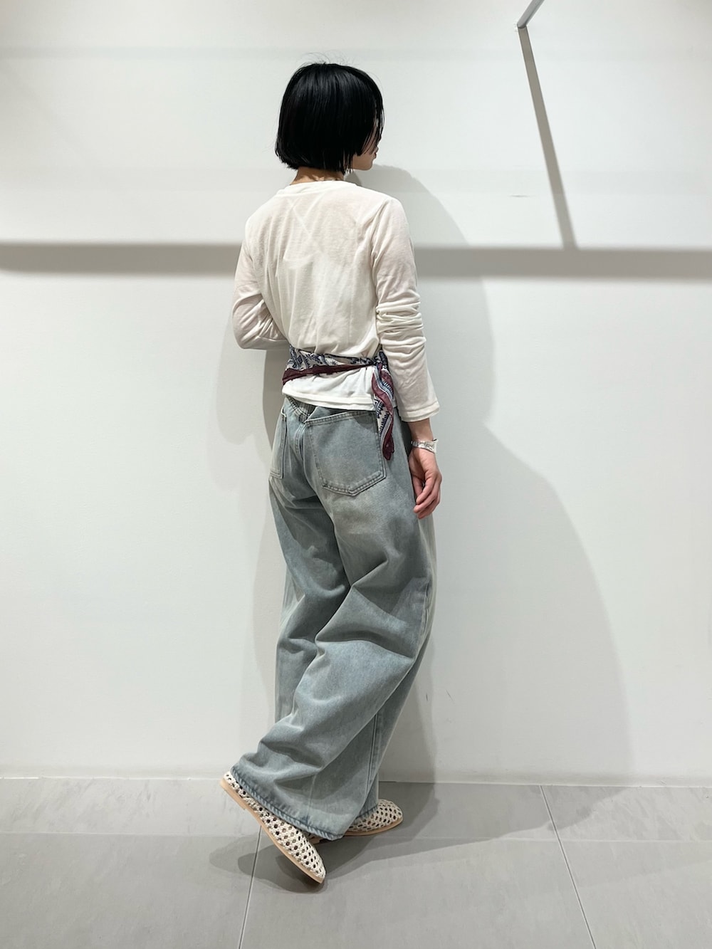 ブルー系のデニムパンツ、ホワイト系のカーディガン/ボレロ、ホワイト系のサンダルを着用したレディースの春コーディネートの3枚目の写真