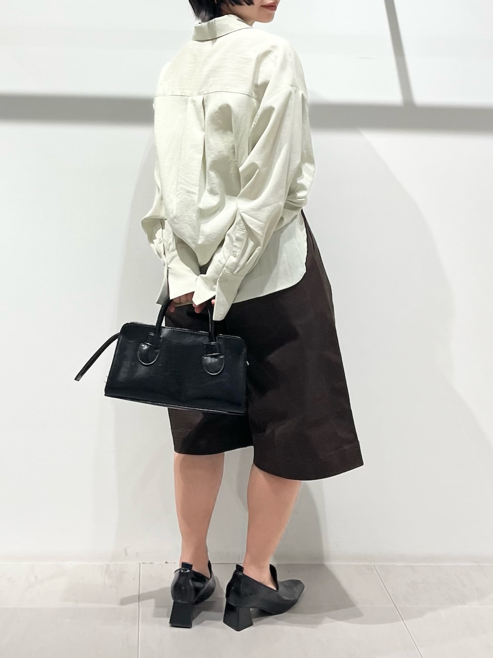 ブラック系のボストンバッグ、ブラック系のパンプス、グリーン系のシャツ/ブラウスを着用したレディースの春コーディネートの3枚目の写真