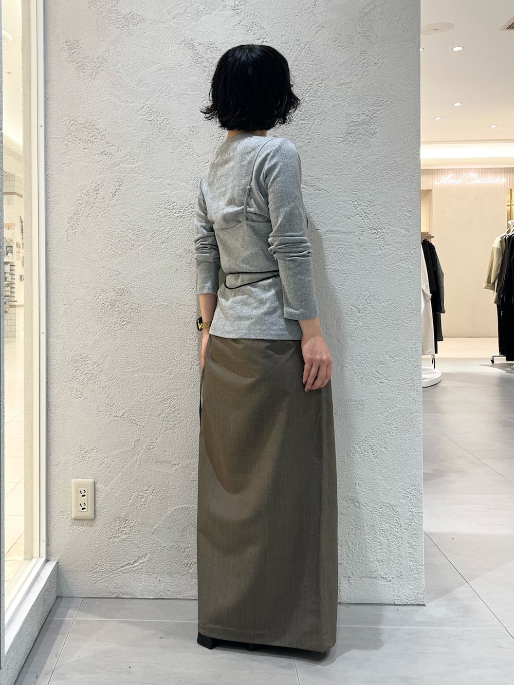 グレー系のTシャツ/カットソー、ベージュ系のスカート、ブラック系のポーチを着用したレディースの秋コーディネートの4枚目の写真