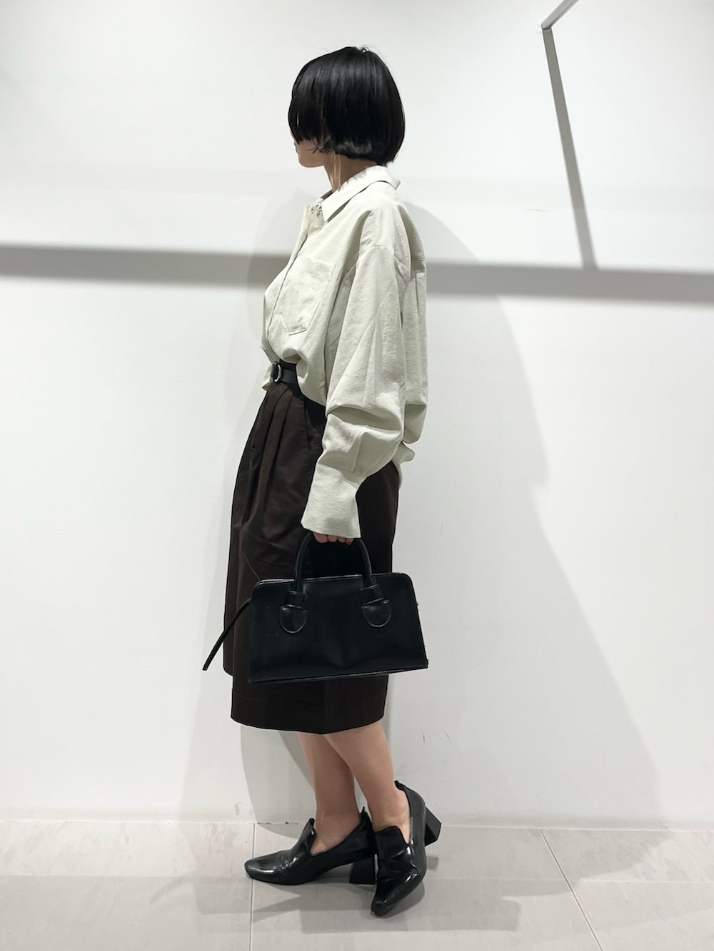 ブラック系のボストンバッグ、ブラック系のパンプス、グリーン系のシャツ/ブラウスを着用したレディースの春コーディネートの2枚目の写真