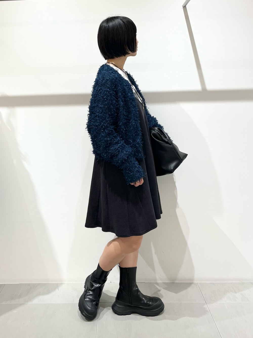 ブルー系のニット/セーター、ブラック系のブーツ、ブラック系のボストンバッグを着用したレディースの秋コーディネートの3枚目の写真