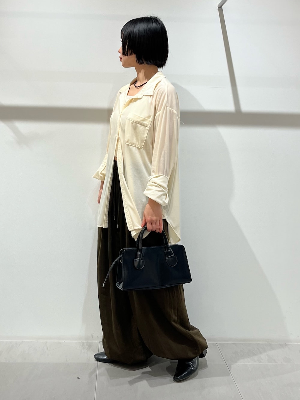 ブラック系のボストンバッグ、ホワイト系のシャツ/ブラウス、ブラック系のパンプスを着用したレディースの冬コーディネートの2枚目の写真