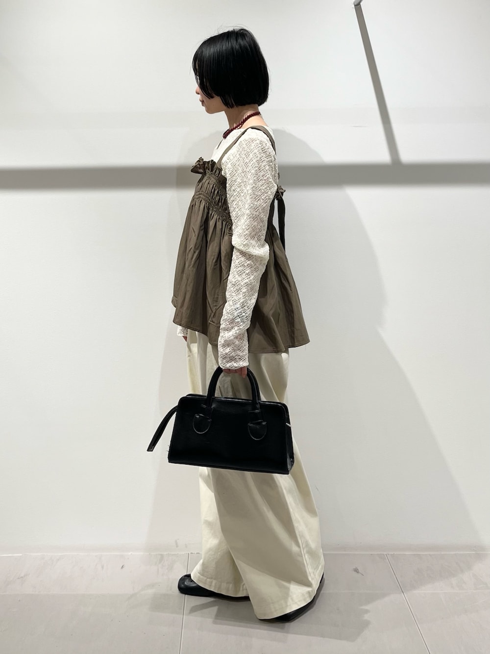 グリーン系のその他トップス、ブラック系のその他シューズ、ホワイト系のその他パンツを着用したレディースの春コーディネートの3枚目の写真