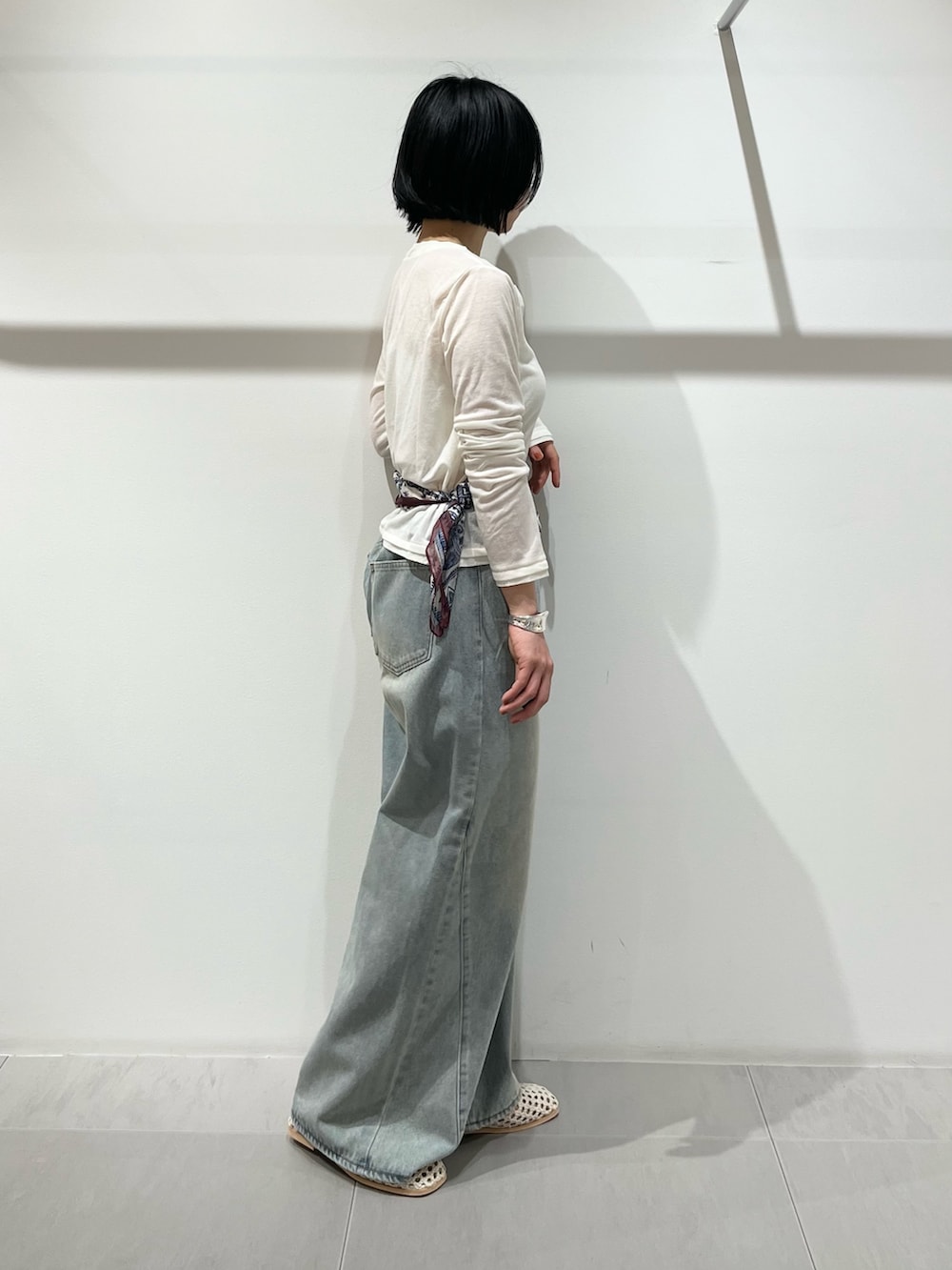 ブルー系のデニムパンツ、ホワイト系のカーディガン/ボレロ、ホワイト系のサンダルを着用したレディースの春コーディネートの2枚目の写真
