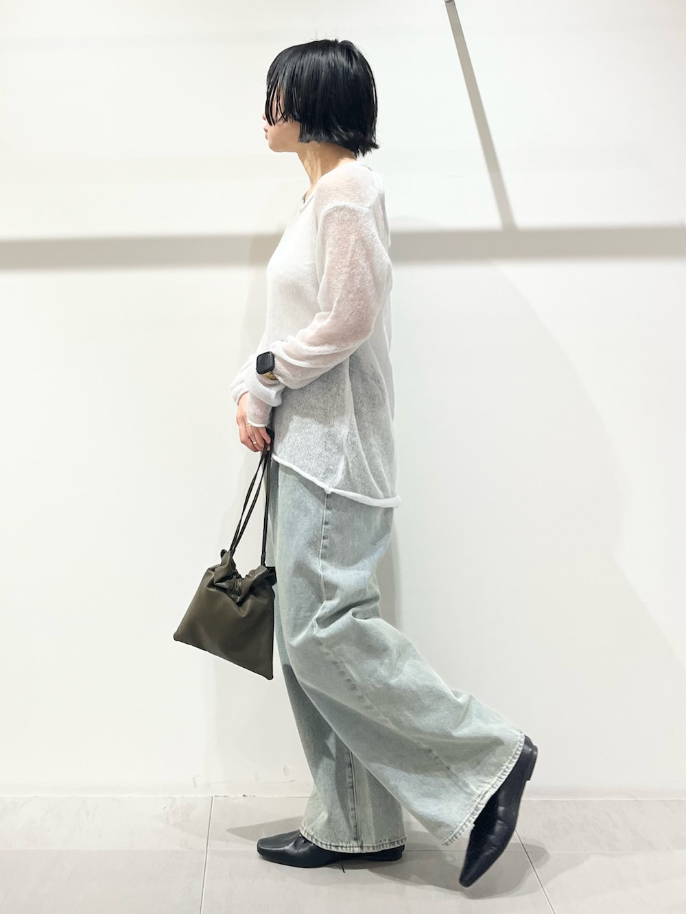 ブラック系のその他シューズ、グリーン系のショルダーバッグ、ブルー系のデニムパンツを着用したレディースの冬コーディネートの2枚目の写真