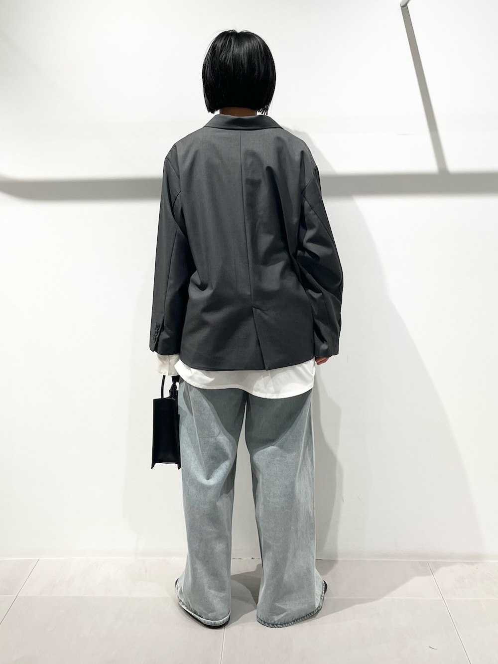 ブラック系のハンドバッグ、ブラック系のその他シューズ、ブルー系のデニムパンツを着用したレディースの春コーディネートの3枚目の写真