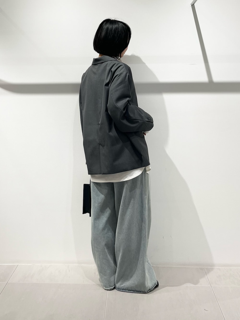 ブラック系のハンドバッグ、ブラック系のその他シューズ、ブルー系のデニムパンツを着用したレディースの春コーディネートの4枚目の写真