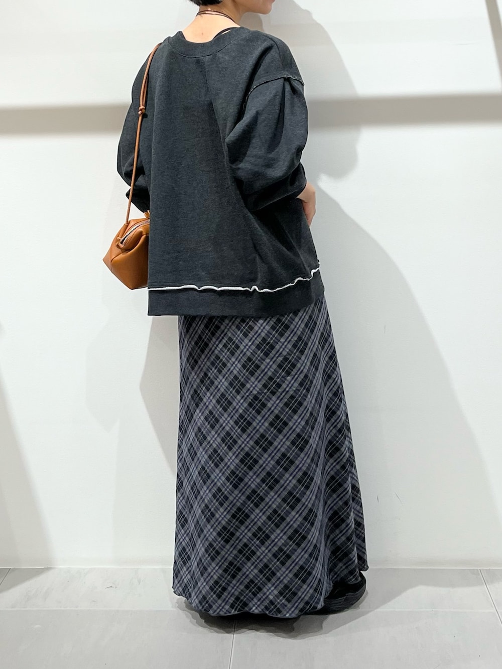 グレー系のTシャツ/カットソー、ブラック系のハンドバッグ、ブルー系のスカートを着用したレディースの秋コーディネートの4枚目の写真