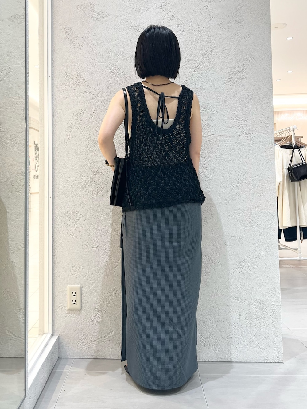 ブラック系のショルダーバッグ、ブラック系のニット/セーター、ブラック系のサンダルを着用したレディースの春コーディネートの3枚目の写真