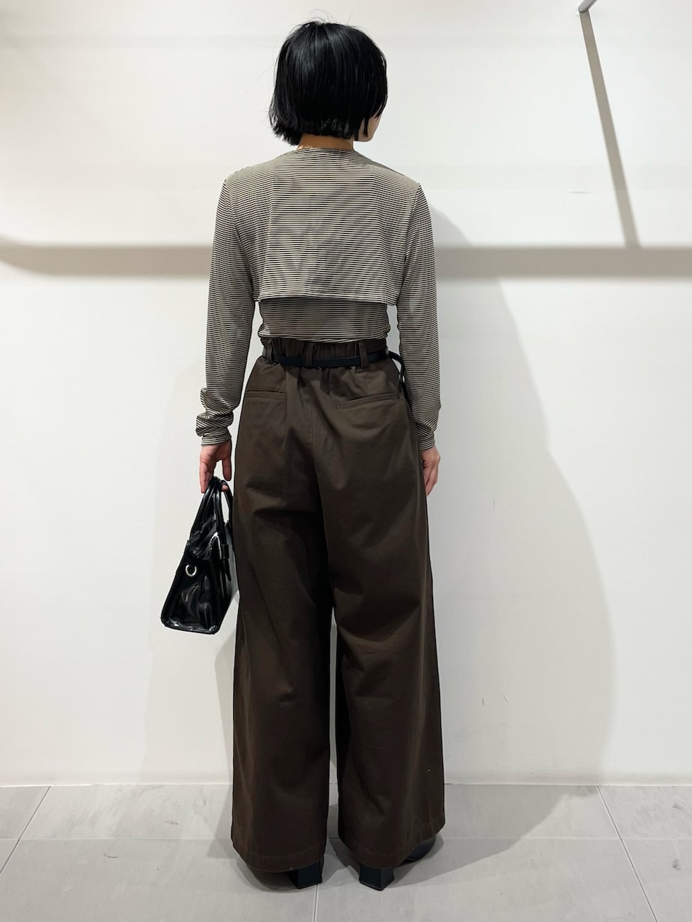 ベージュ系のキャミソール、ブラウン系のその他パンツ、ブラック系のボストンバッグを着用したレディースの春コーディネートの3枚目の写真