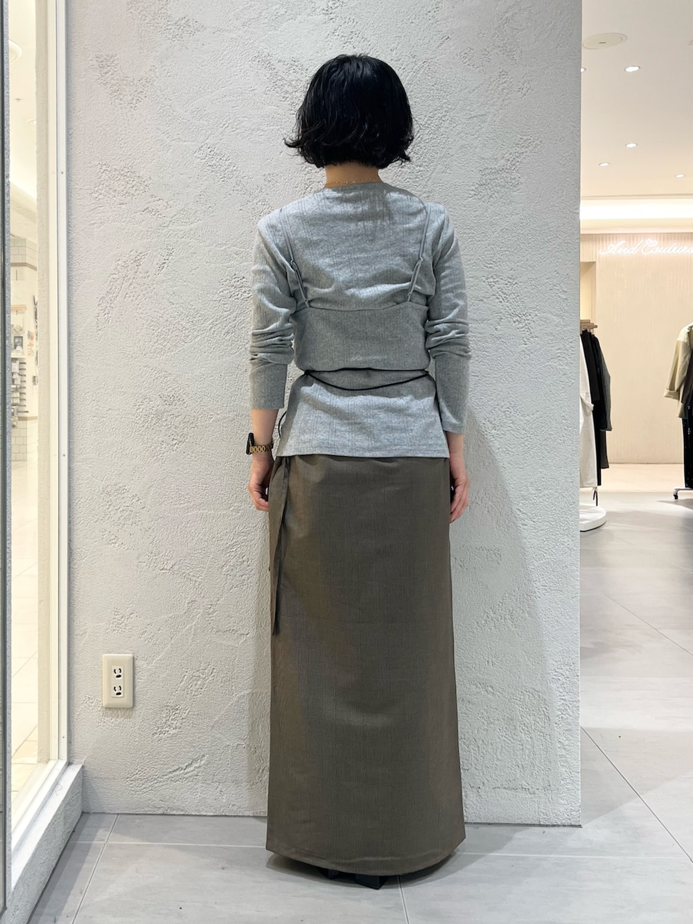 グレー系のTシャツ/カットソー、ベージュ系のスカート、ブラック系のポーチを着用したレディースの秋コーディネートの3枚目の写真
