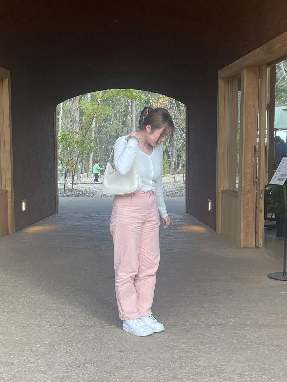 ピンク系のデニムパンツ、ホワイト系のスニーカー、ホワイト系のハンドバッグを着用したレディースの春コーディネートの2枚目の写真