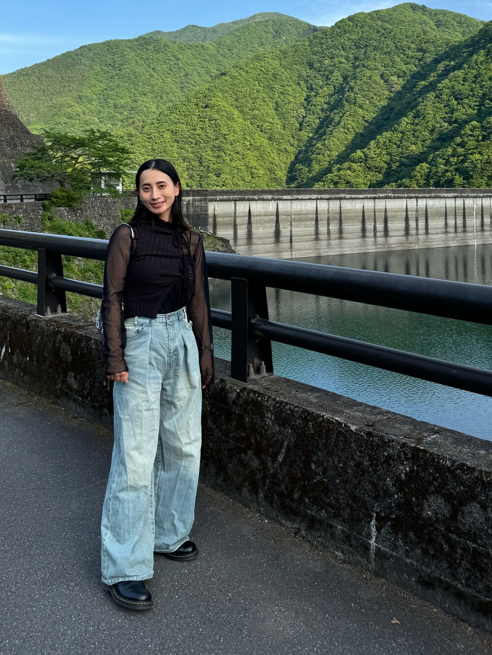 ブラック系のタンクトップ、シルバー系のショルダーバッグ、ブルー系のデニムパンツを着用したレディースの春コーディネートの2枚目の写真