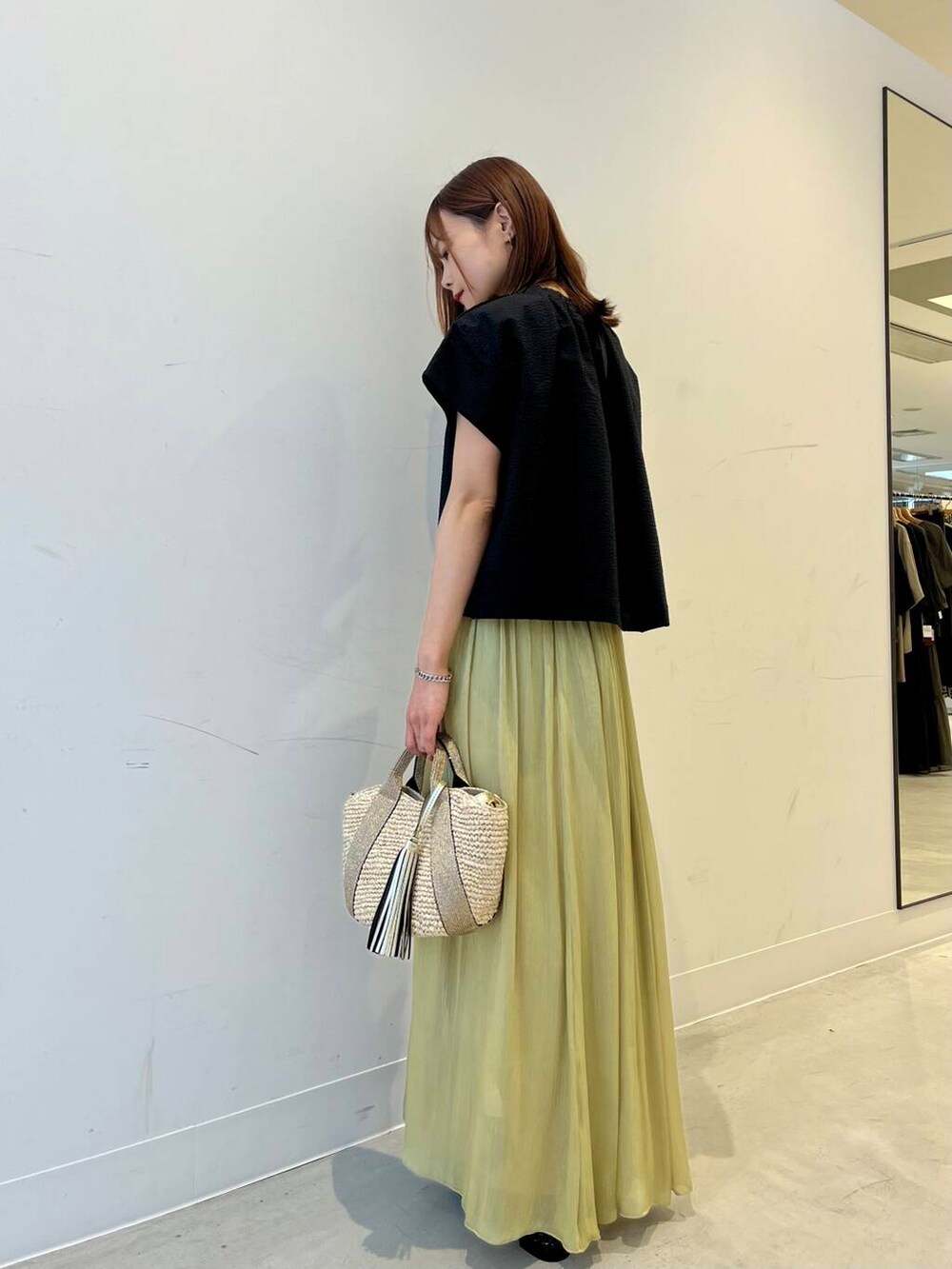ベージュ系のかごバッグ、ブラック系のバレエシューズ、グリーン系のスカートを着用したレディースの春コーディネートの4枚目の写真
