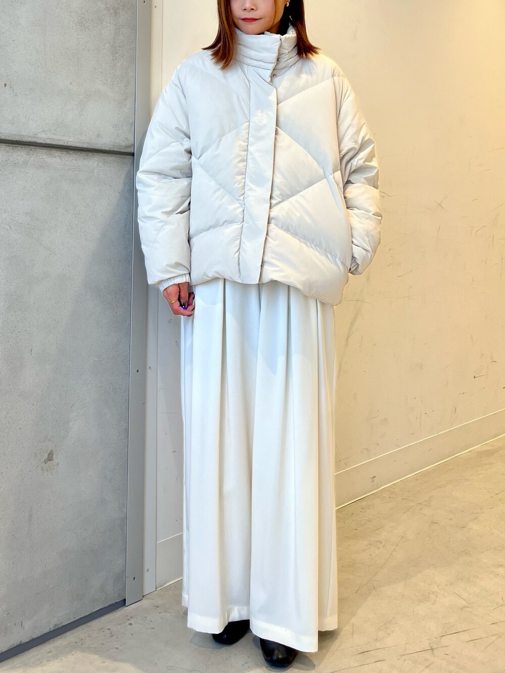 ホワイト系のダウンジャケット/コート、ブラウン系のニット/セーター、ホワイト系のその他パンツを着用したレディースの冬コーディネートの4枚目の写真