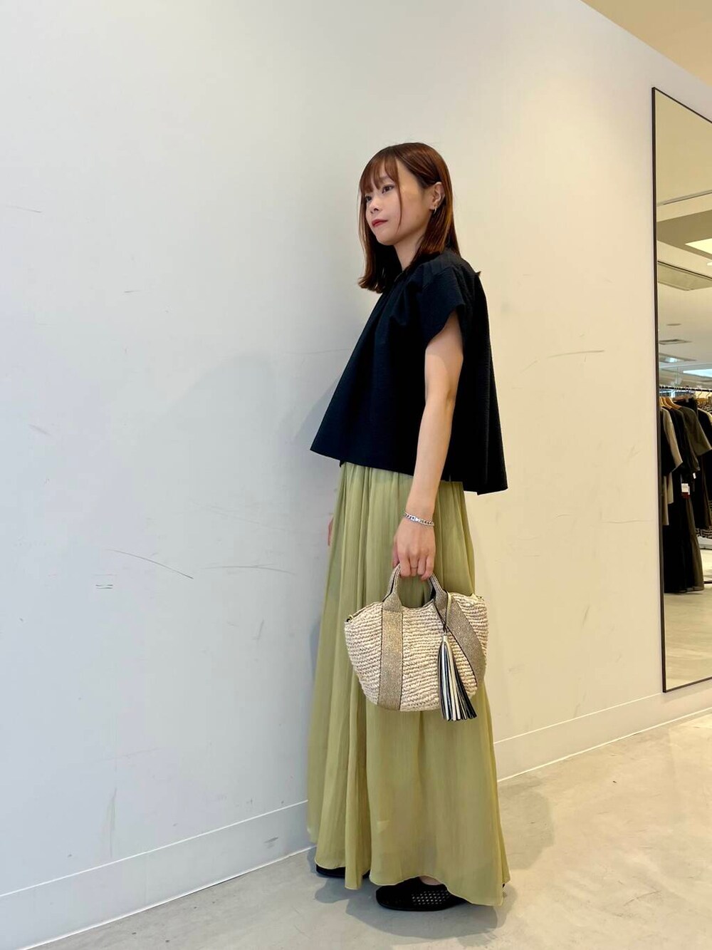 ベージュ系のかごバッグ、ブラック系のバレエシューズ、グリーン系のスカートを着用したレディースの春コーディネートの3枚目の写真