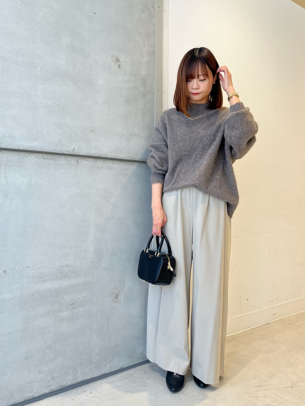 ブラウン系のニット/セーター、ベージュ系のその他パンツ、ブラック系のショルダーバッグを着用したレディースの秋コーディネートの5枚目の写真